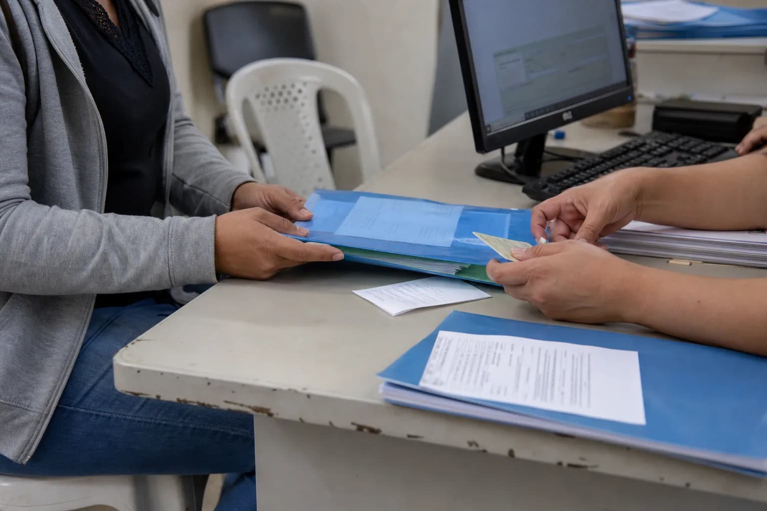 Candidata entrega documentos para conferência do Cadastro Único em atendimento público.